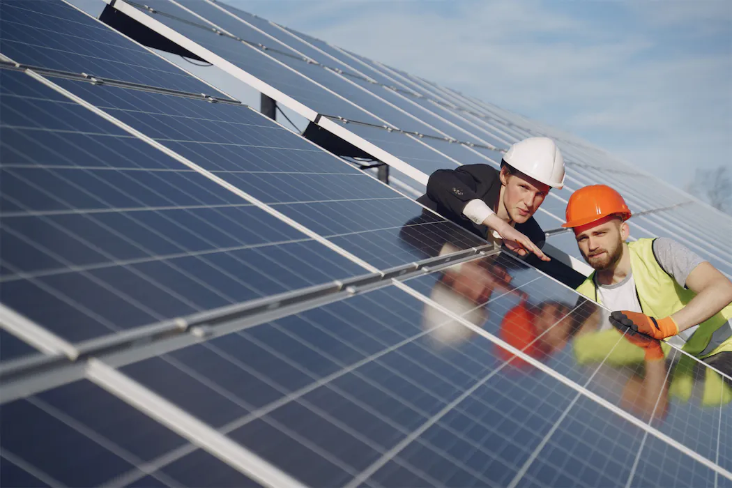 Professional solar installers inspecting solar panel array during combined roof and solar installation, demonstrating quality control and expertise in renewable energy systems